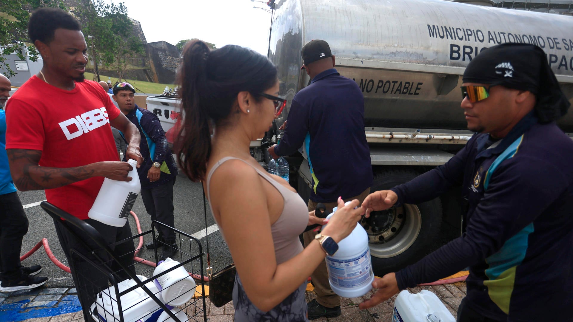 Personas se abastecen de agua tras la interrupción del servicio este lunes, en San Juan (Puerto Rico). EFE/Thais Llorca