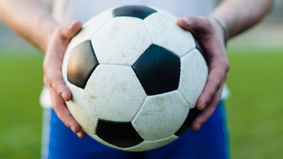 Deportista de cultivos mostrando el balón de fútbol