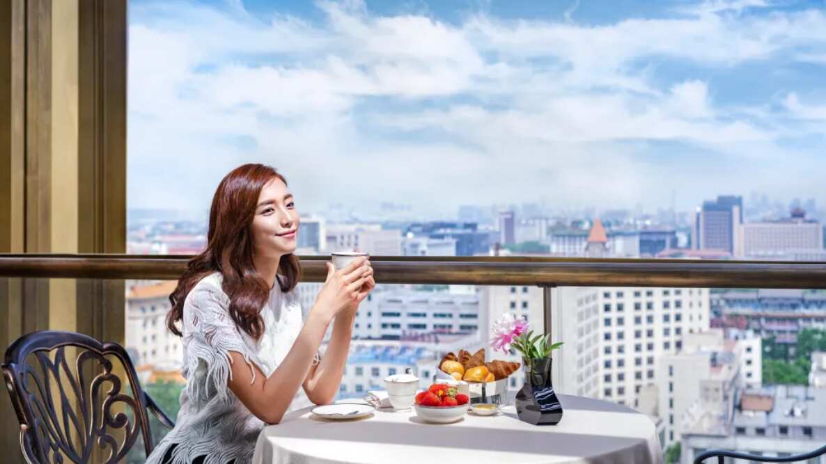 Mujer sentada en una mesa tomando de una taza.